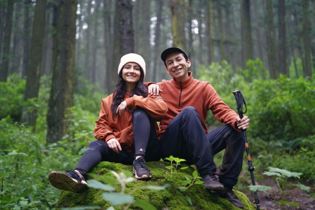 Happy couple sitting together on mossy rock during forest hike after learning how to fix a broken relationship
