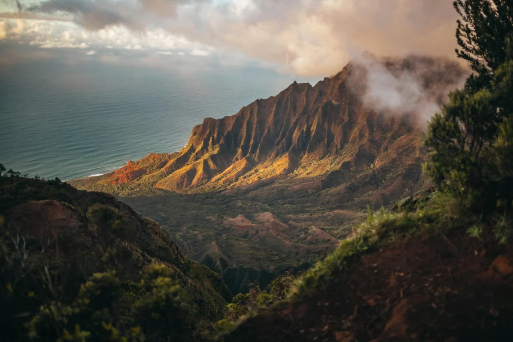 Kalalau Valley ridgeline at sunset, Kauai, Hawaii - dramatic eroded mountain cliffs meeting the Pacific Ocean with golden hour lighting