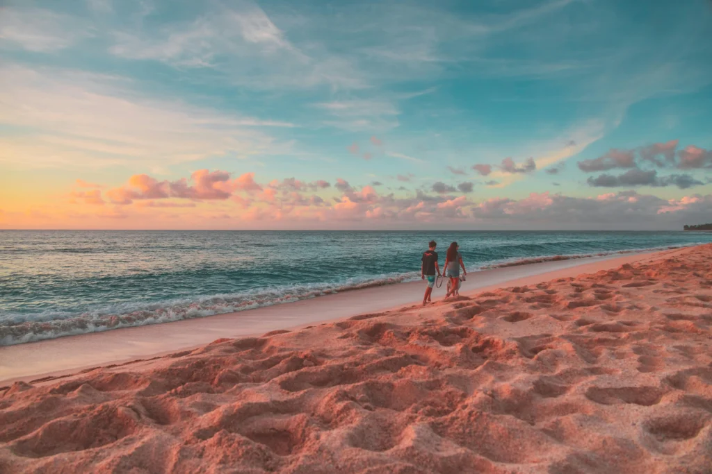 Couple holding hands walking along beach at sunset in Hawaii - how to get a girlfriend in Hawaii by enjoying romantic beach dates and island activities together
