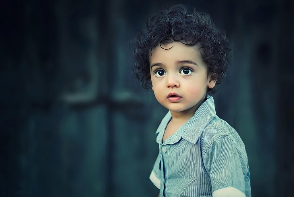 Curly-haired toddler looking at the camera, representing early childhood development and when do toddlers start talking