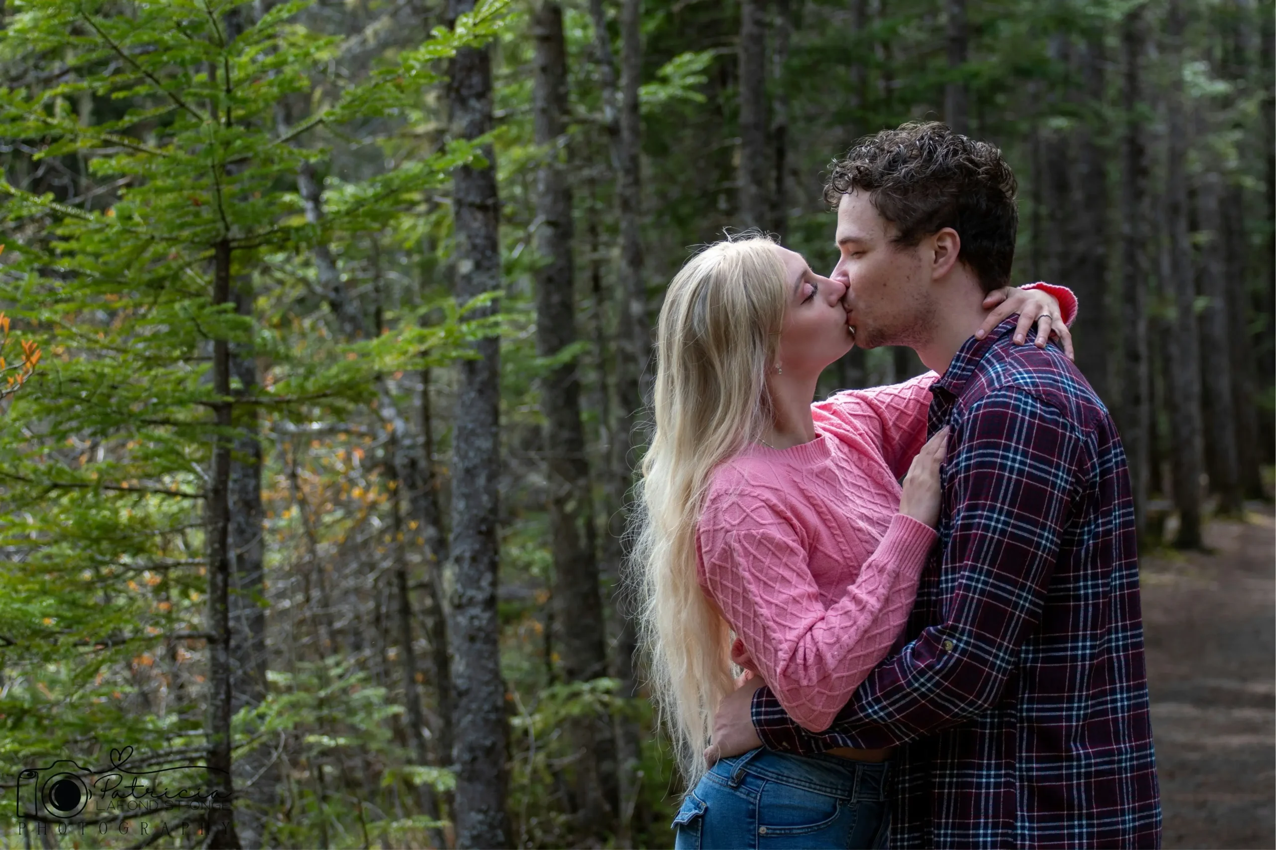the emotional connection and balance found in cancer and sagittarius relationship compatibility being highlighted. The woman, with long blonde hair and a pink sweater, has her arm around the man, who is wearing a plaid shirt, with a background of dense green evergreen trees.