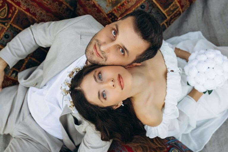 Couple in classic bride and groom costumes lying together in white wedding attire for romantic couple costumes inspiration