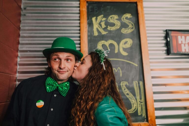 Couple in festive Irish-themed costumes with green accessories and shamrock decorations for St. Patrick's Day celebration