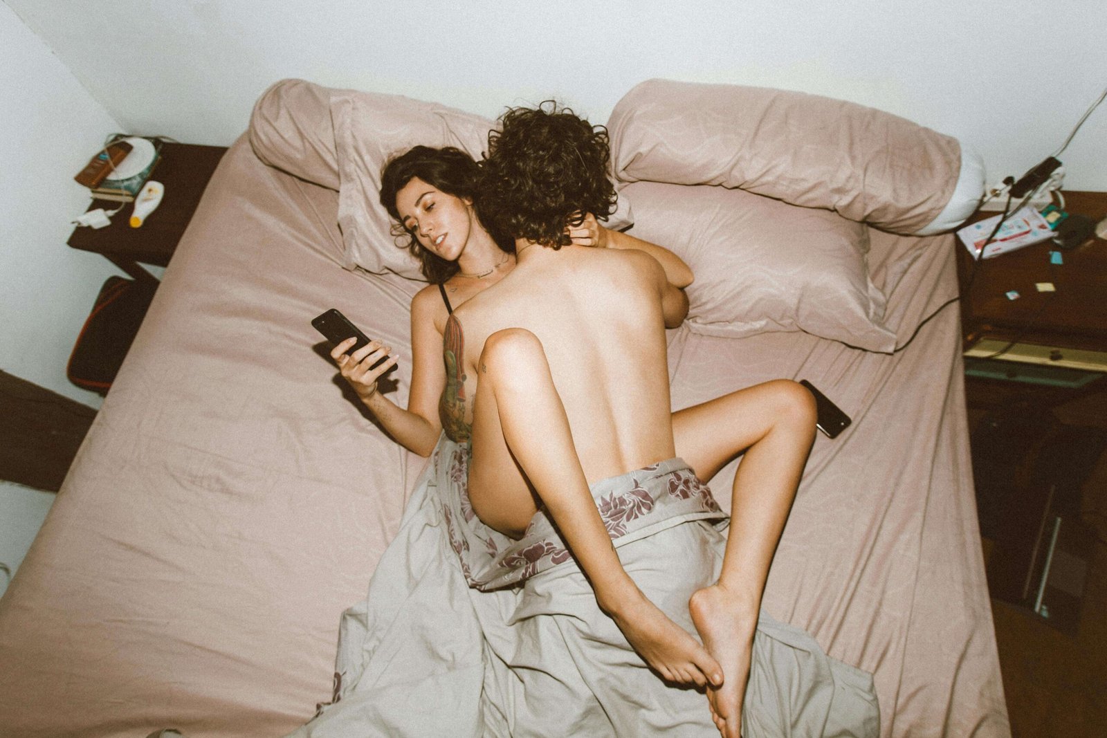 How often do married couples with kids have sex - Overhead view of couple in bed with woman on phone, illustrating common modern challenges to maintaining intimacy and physical connection in relationships