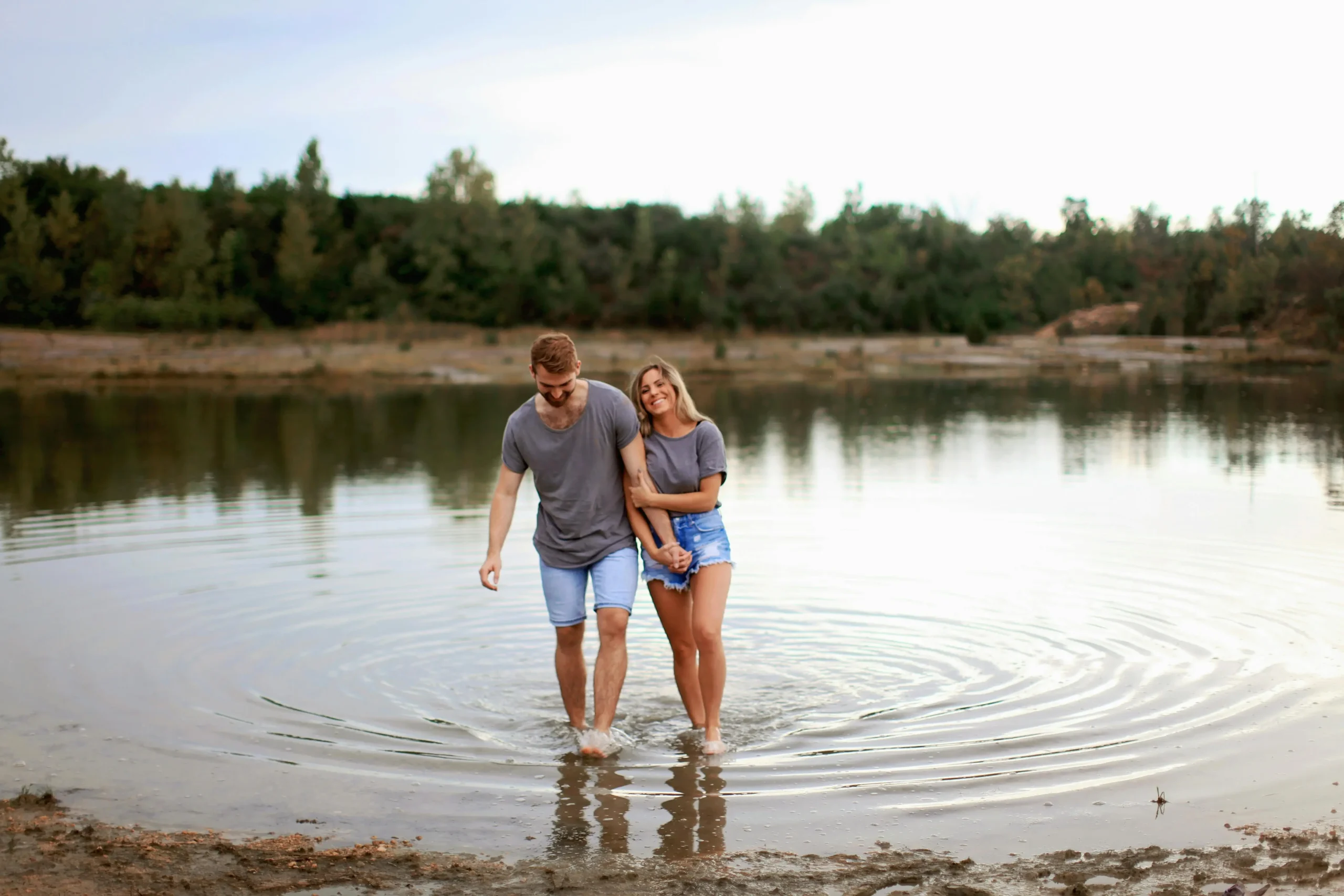 How to rebuild trust in a relationship - Young couple holding hands and walking together in shallow lake water, symbolizing reconnection and healing after broken trust