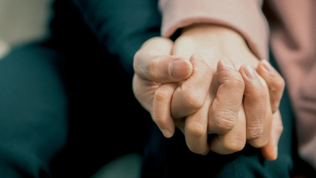 A close-up of a couple holding hands, symbolizing emotional connection and trust, illustrating how to fall back in love with your spouse.