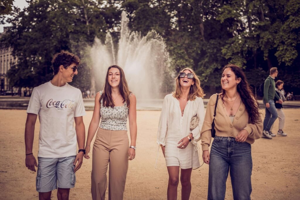 Group of four friends walking together in a park near a fountain, representing the complex emotions of why do I feel sad after hanging out with friends