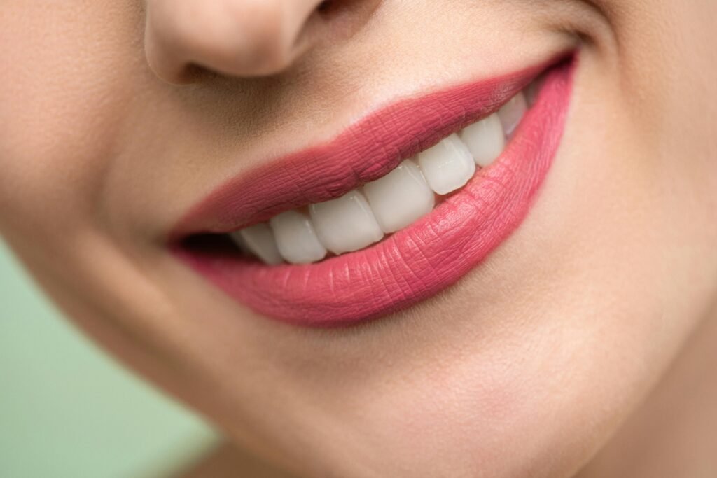 Close-up of a smiling mouth with pink lips and healthy teeth, illustrating how soon can you talk after wisdom teeth removal